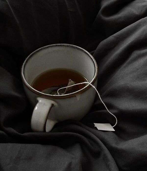 Kop thee met losse theeblaadjes op een rustige tafel